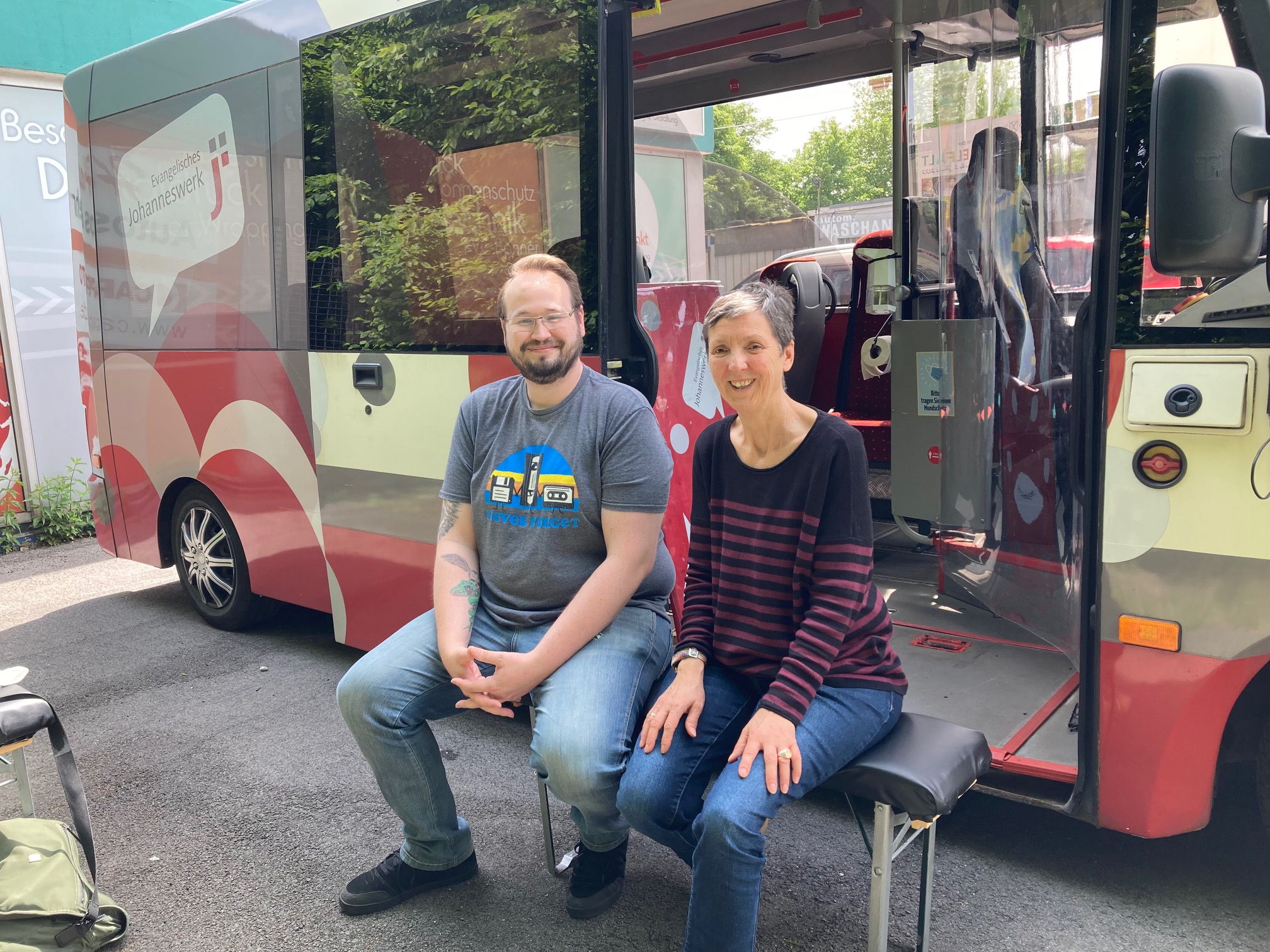 Ein Mann und eine Frau sitzen vor einem Bus.