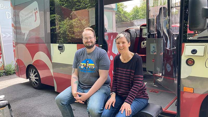 Ein Mann und eine Frau sitzen vor einem Bus.